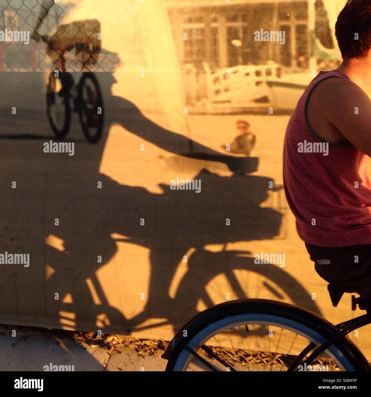 Ciclista con murale di biciclette e noleggio di ombre, tardo pomeriggio Foto Stock