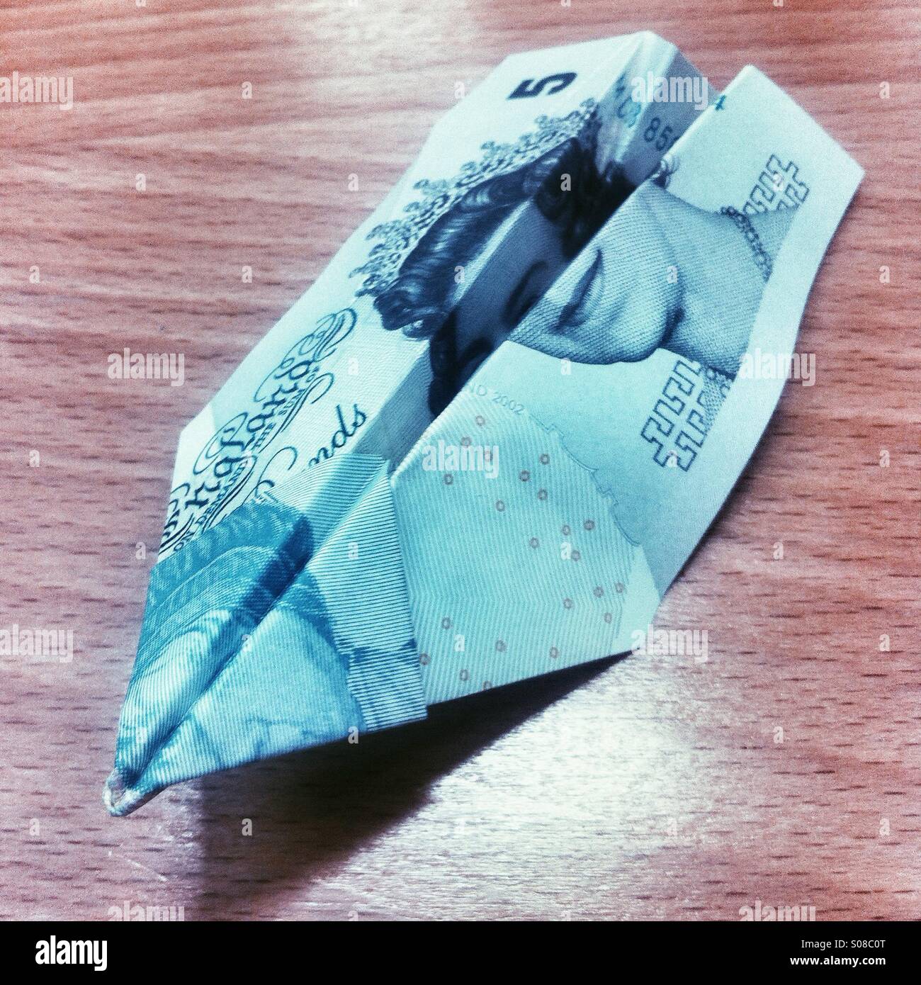 Cinque pound nota ripiegato in un aeroplano di carta - Immagine stock catturata con smartphone