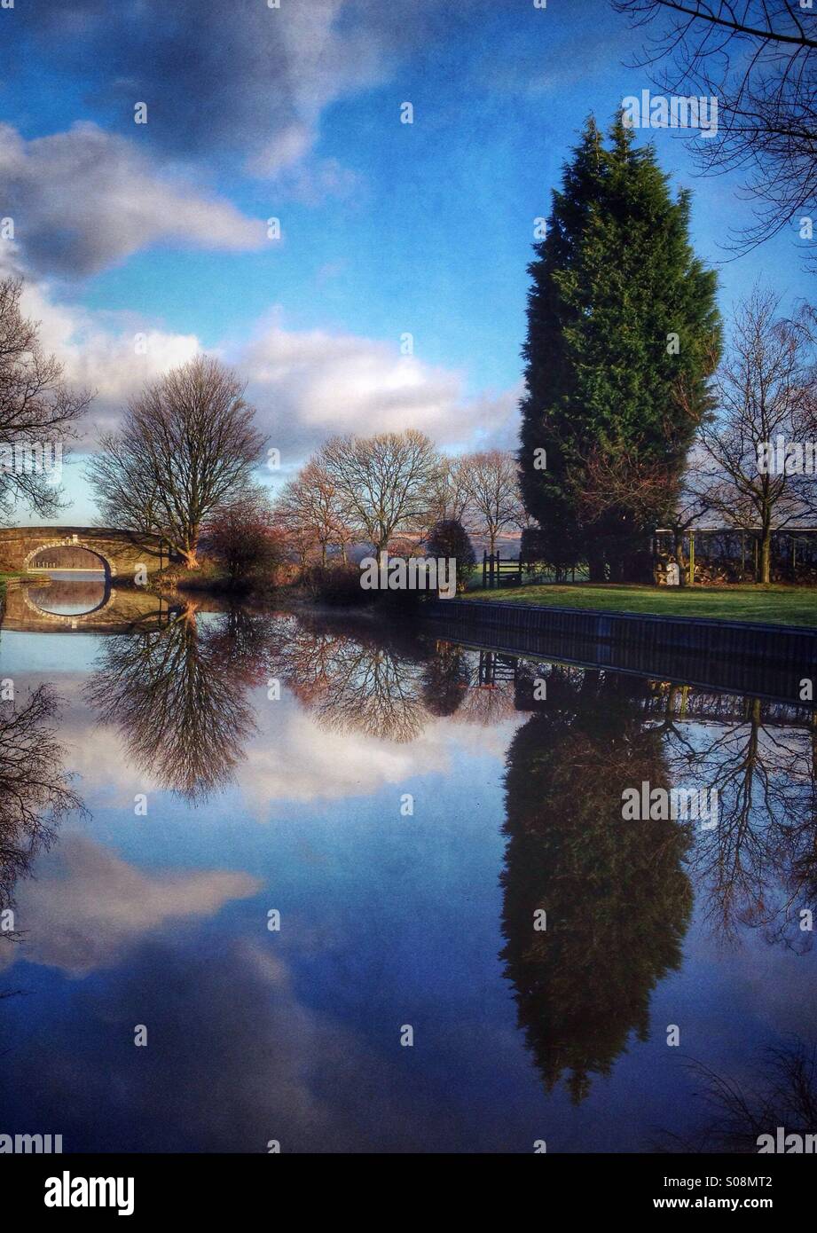 Immagine a specchio di riflessione del ponte e alberi in canale. Leeds Liverpool canal vicino Adlington in Lancashire Foto Stock