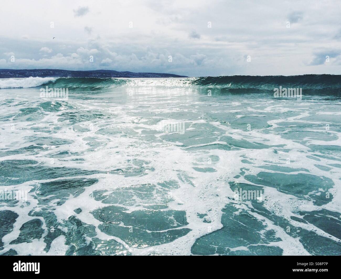 In onda il mare con la terra in distanza Foto Stock