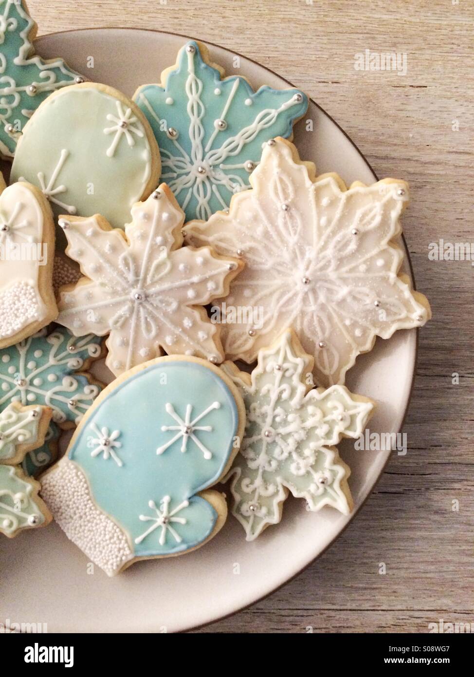 Smerigliato zucchero vacanze cookie disposti su una piastra di crema seduto su di un legno rustico sfondo. Foto Stock