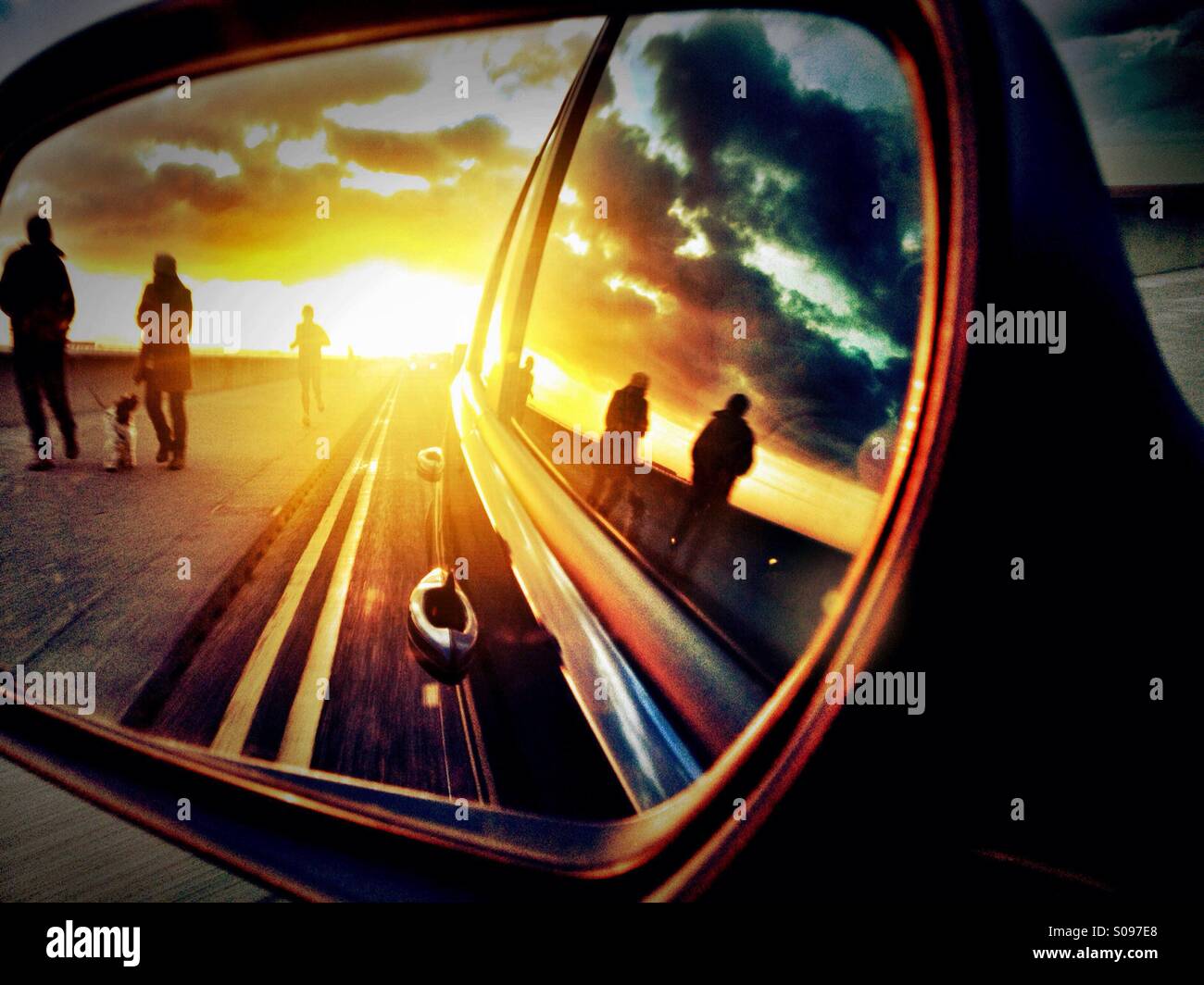 Il tramonto e la gente camminare come sembrano attraverso auto specchio laterale Foto Stock