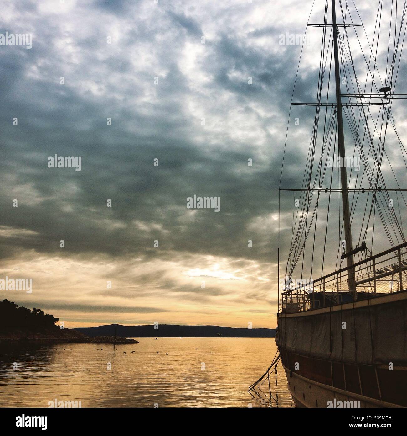 Imbarcazione a vela in porto con drammatico sfondo cielo Foto Stock