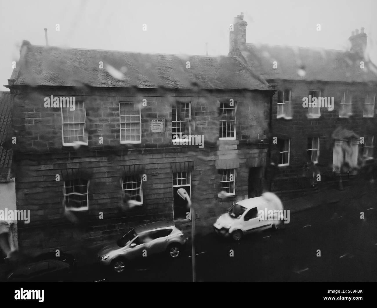 Misere clima britannico - heavy rain su una finestra che si affacciava su una strada residenziale nel Northumberland, Regno Unito. Foto Stock