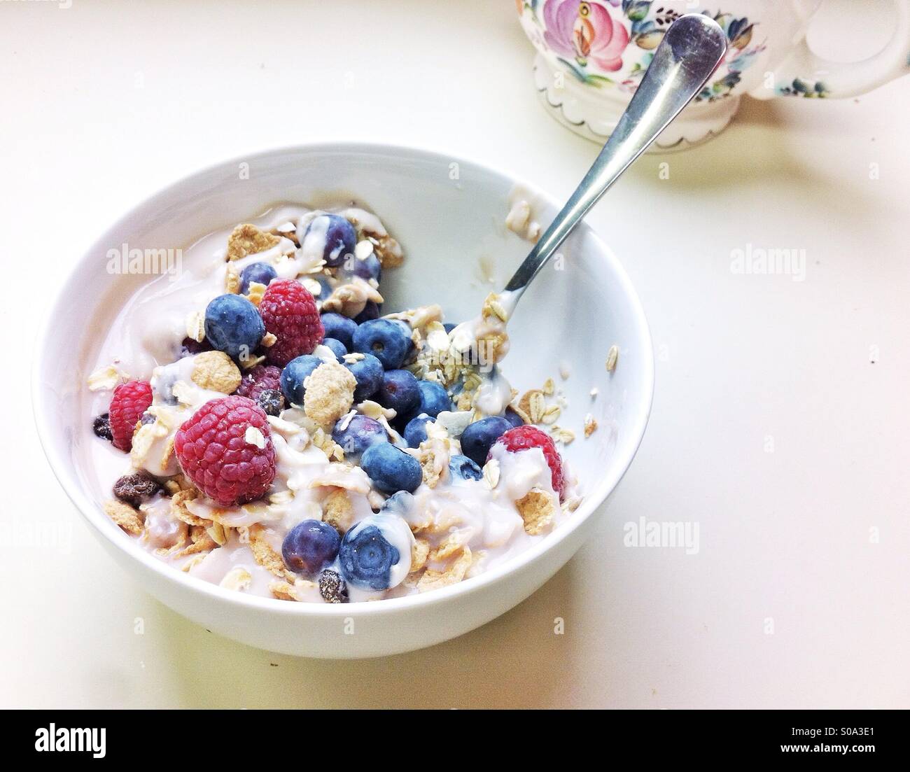Colazione Leggera di cereali, yogurt di soia, lamponi e mirtilli nella ciotola bianco Foto Stock