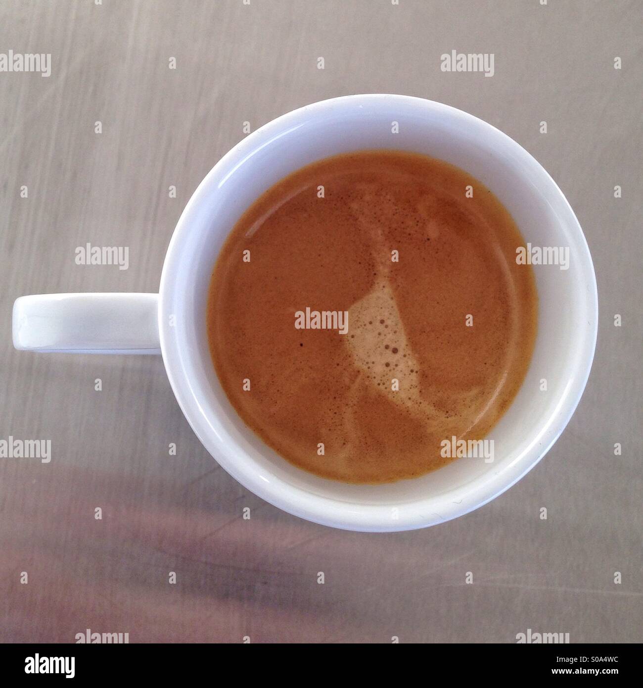 Caffè espresso in una piccola tazza bianca su un metallo con la superficie di alluminio, un bel giallo di schiuma di caffè sulla parte superiore, coppa circolare Foto Stock