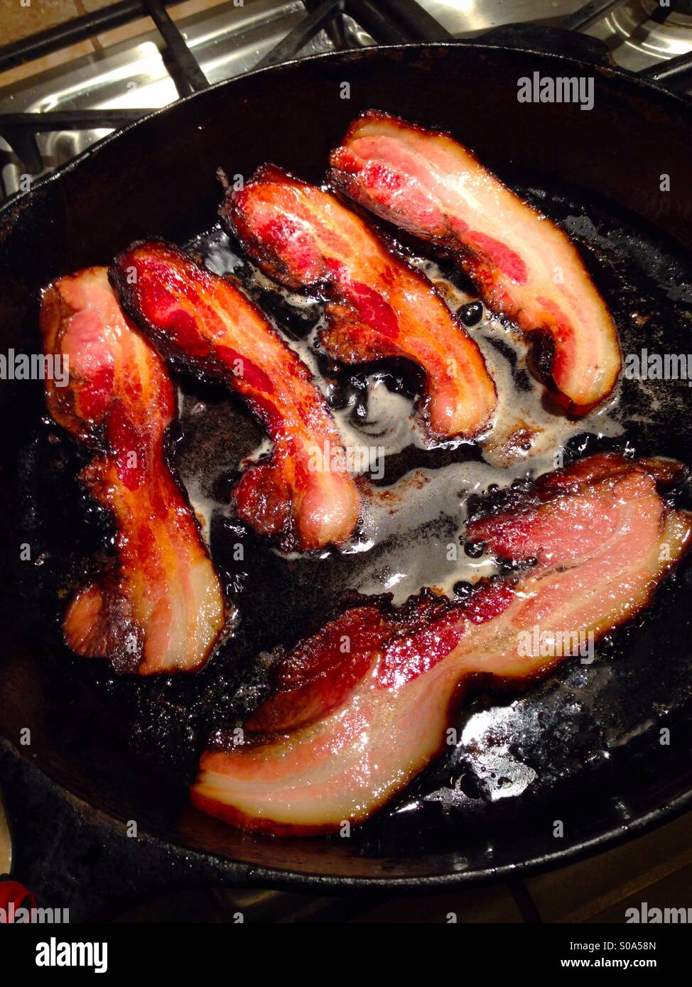 Strisce di pancetta sfrigolante in un ferro da stiro padella - Immagine stock catturata con smartphone