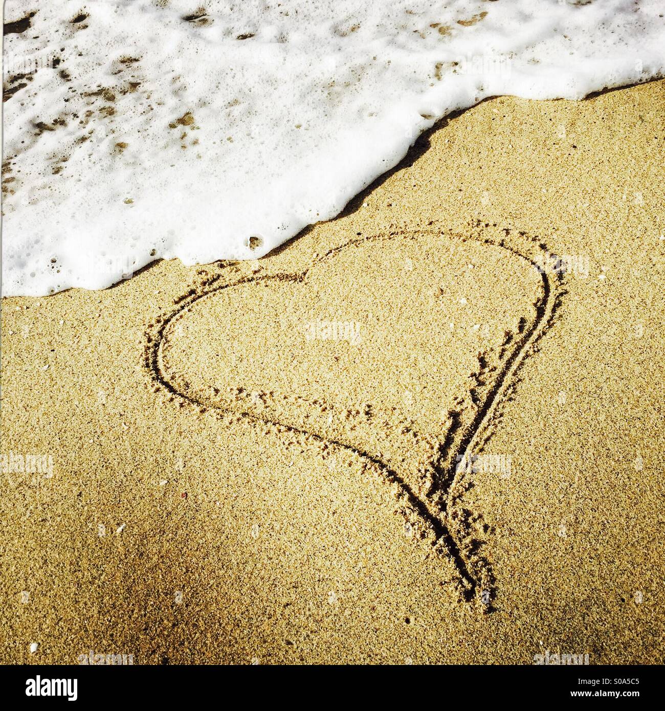 Un cuore disegnato nella sabbia al litorale. Manhattan Beach, California USA. - Immagine stock catturata con smartphone