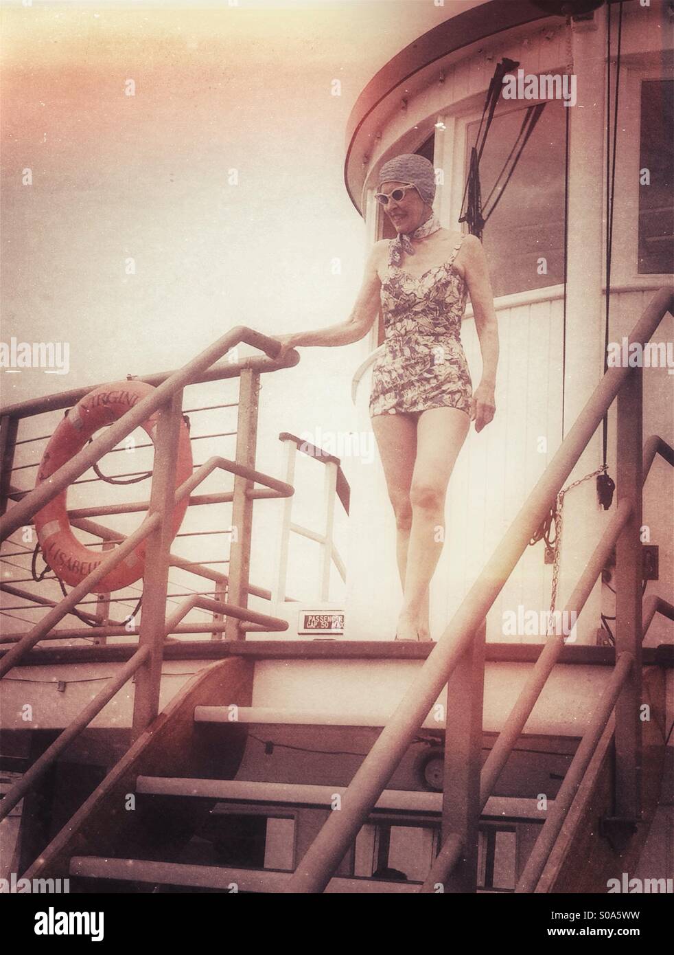 Donna anziana della modellazione di un 1920s vintage costume da bagno su una scheda di vintage nave di legno Foto Stock