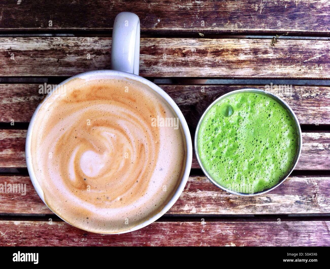 Tazza di cappuccino e bicchiere di succo verde sulla tavola in legno rustico Foto Stock