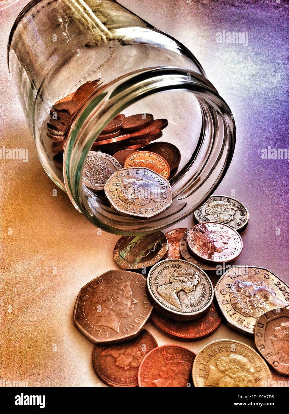 Monete fuoriuscita dal vaso di vetro Foto Stock