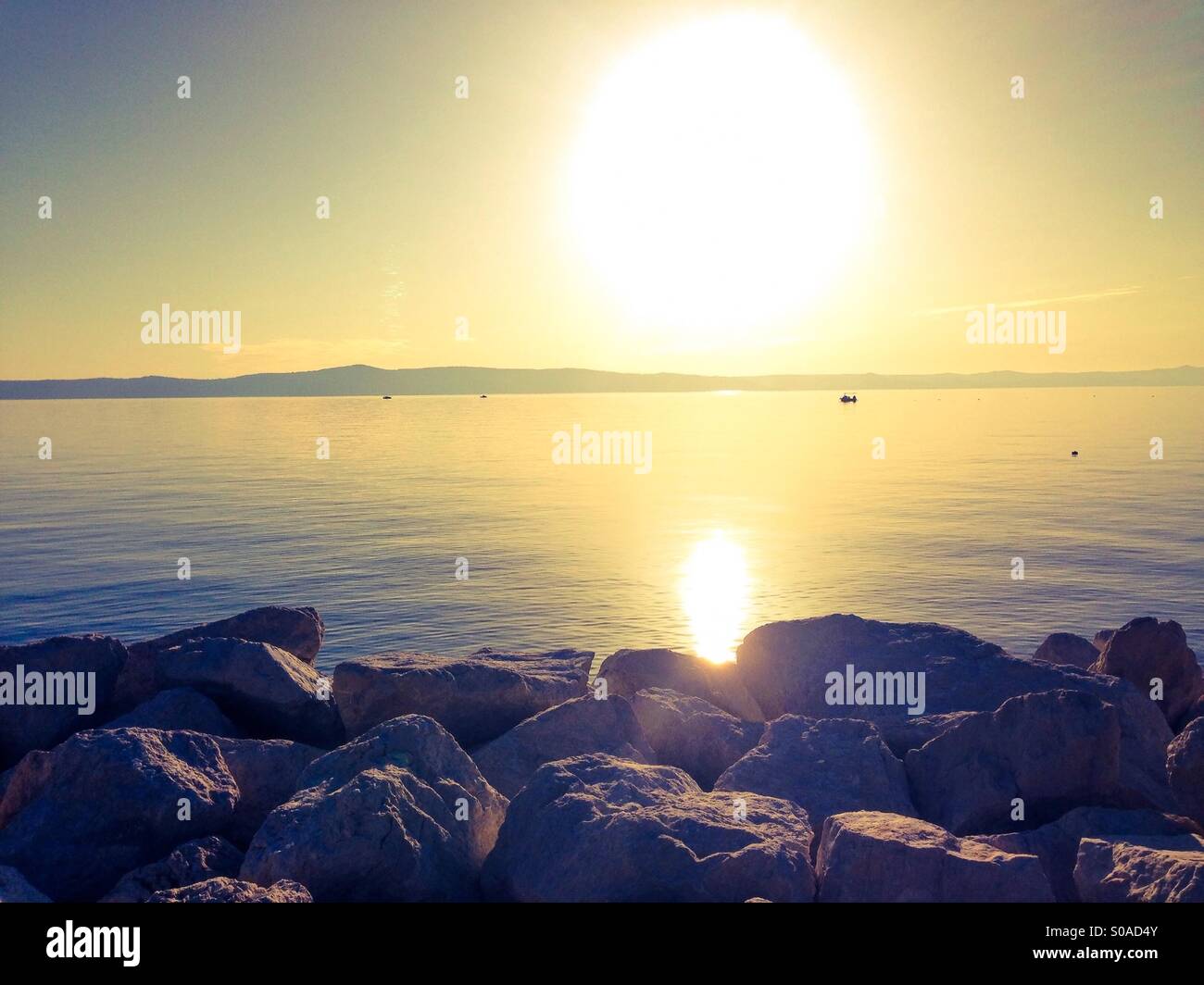 Vista al tramonto sul mare calmo dalla costa rocciosa Foto Stock