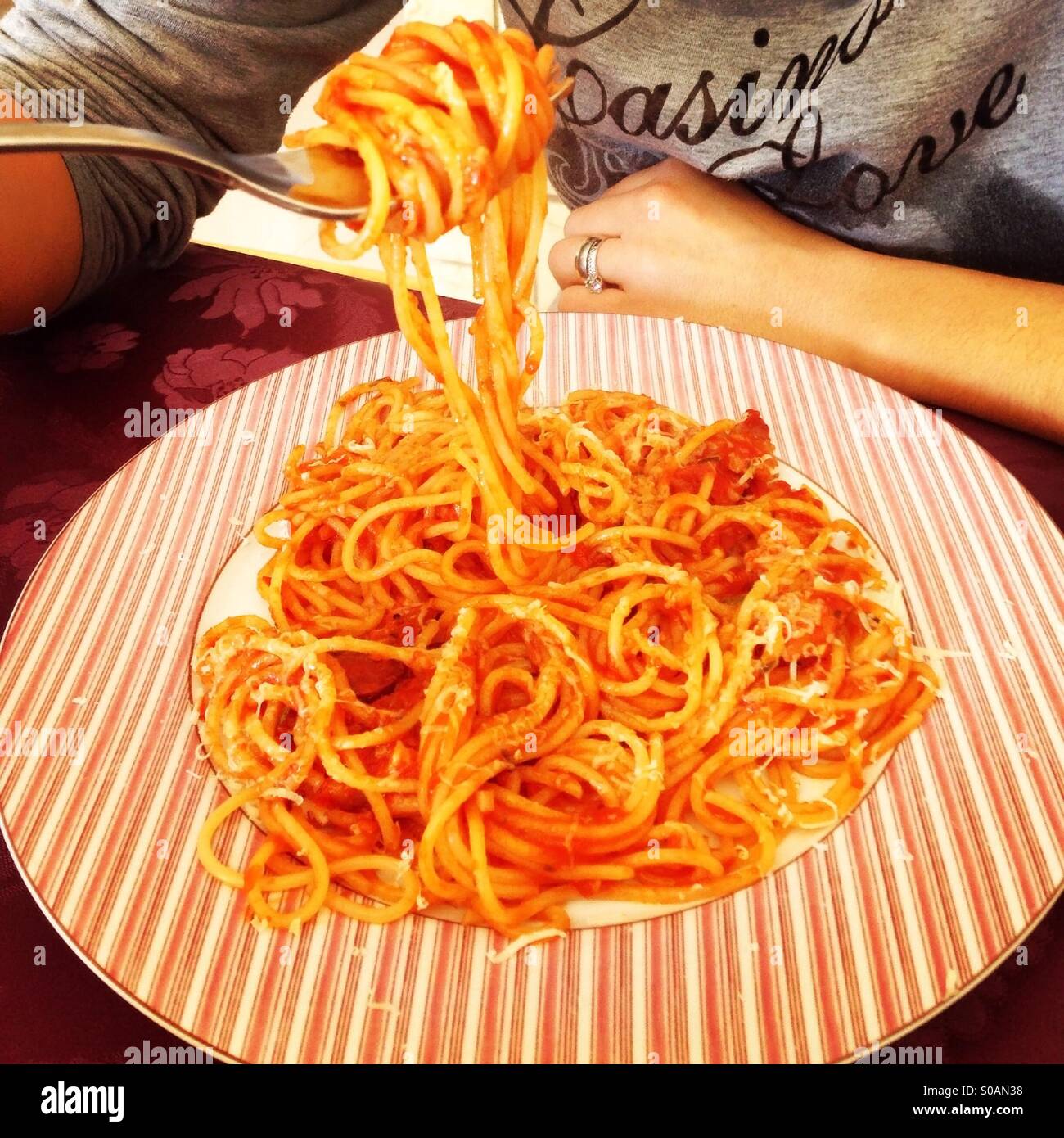Donna mangiare spaghetti con sugo di pomodoro e formaggio parmigiano Foto Stock