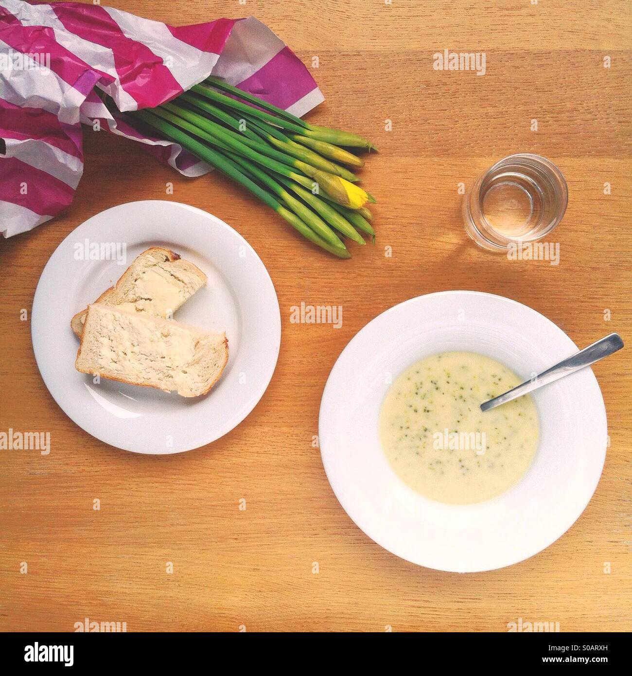 Una ciotola di Stilton e broccoli zuppa di pane e fiori recisi, dall'alto. - Immagine stock catturata con smartphone