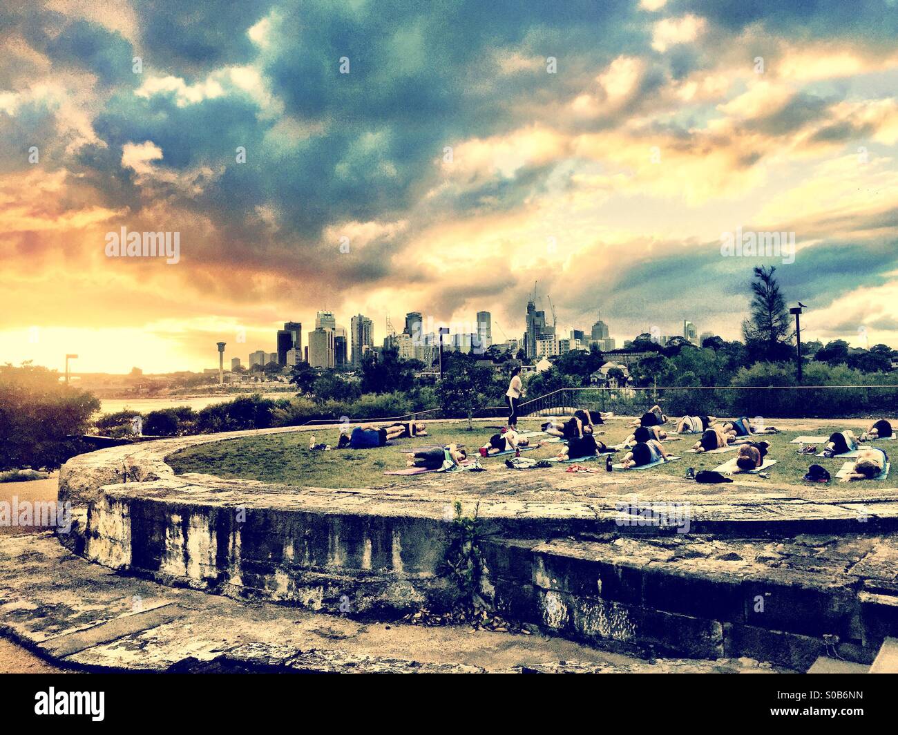 Una classe di yoga all'alba in un parco che si affaccia su Sydney Foto Stock