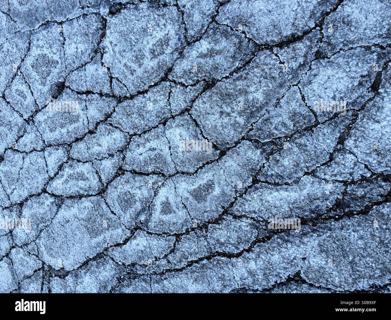 Inverno astratto: Dettaglio di asfalto screpolato pavimentazione del parcheggio sbiancato con sale di circolazione su strada Foto Stock