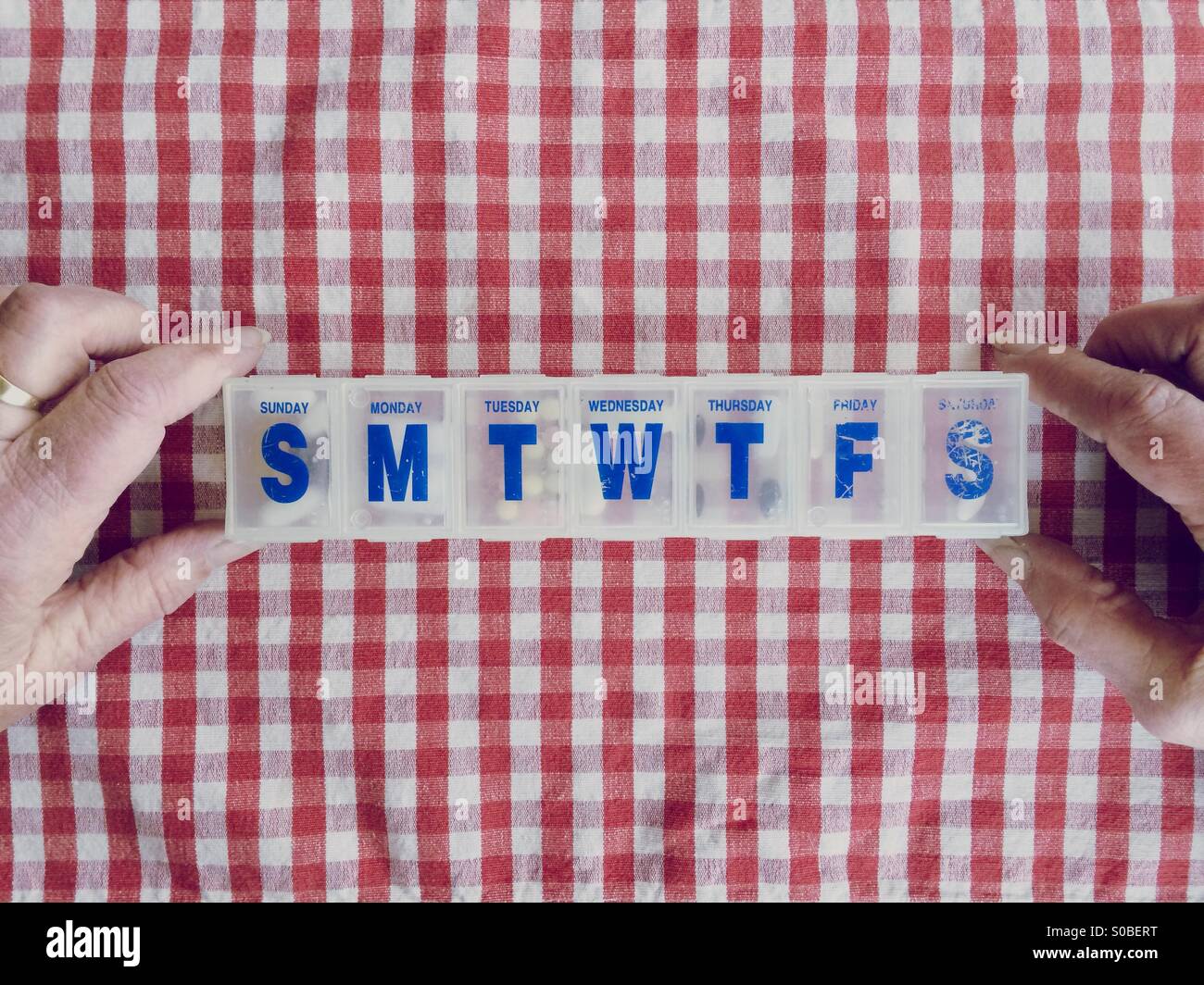 Una signora anziana del punto di vista della sua scatola di pillole pieno di farmaci e supplementi. Foto Stock