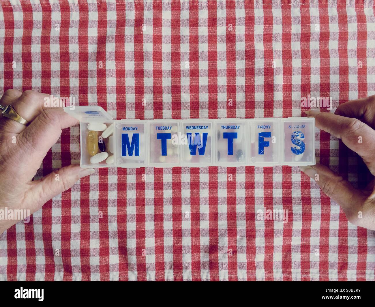 Una signora anziana del punto di vista della sua scatola di pillole pieno di farmaci e supplementi. Foto Stock