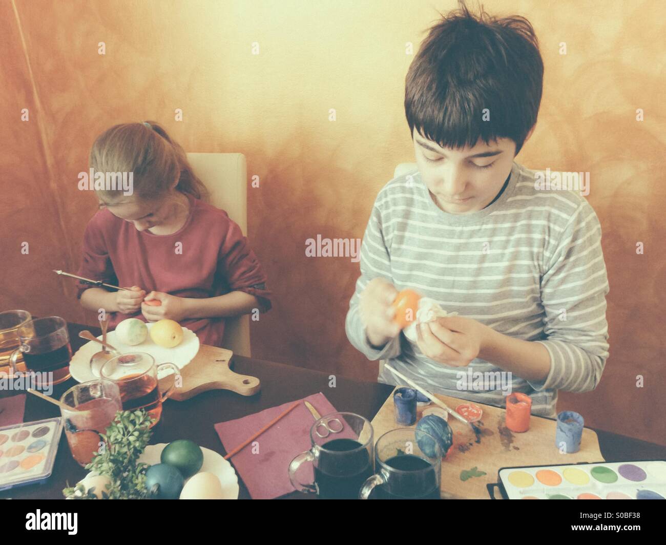 Fratello e Sorella di pittura delle uova di Pasqua in casa Foto Stock