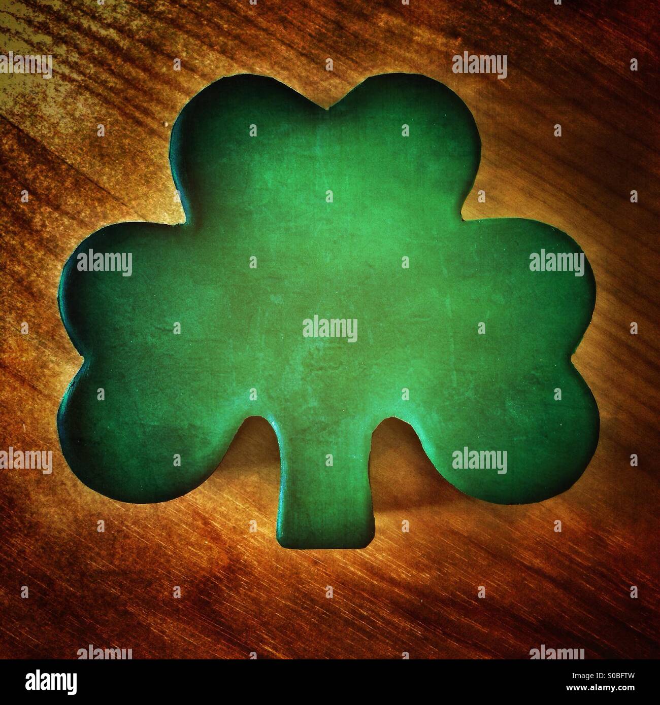 Shamrock forma sul buio di una superficie di legno. - Immagine stock catturata con smartphone