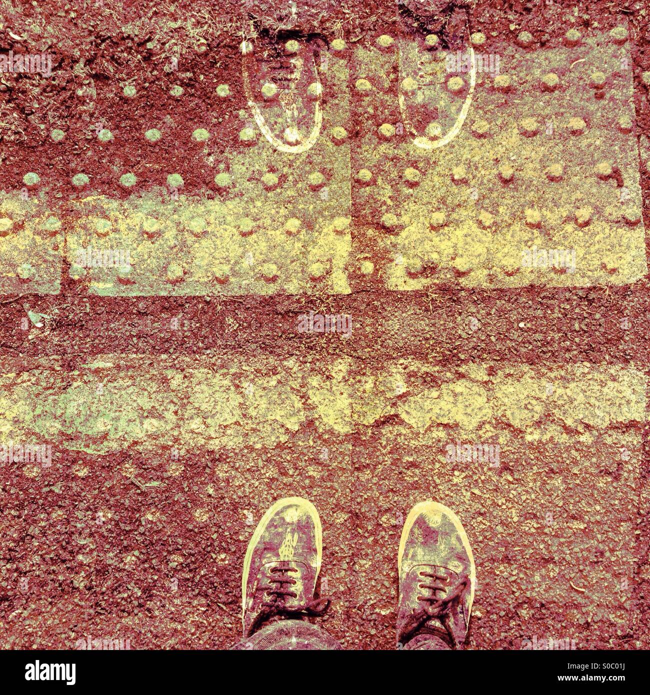 In piedi dietro le linee di colore giallo Foto Stock