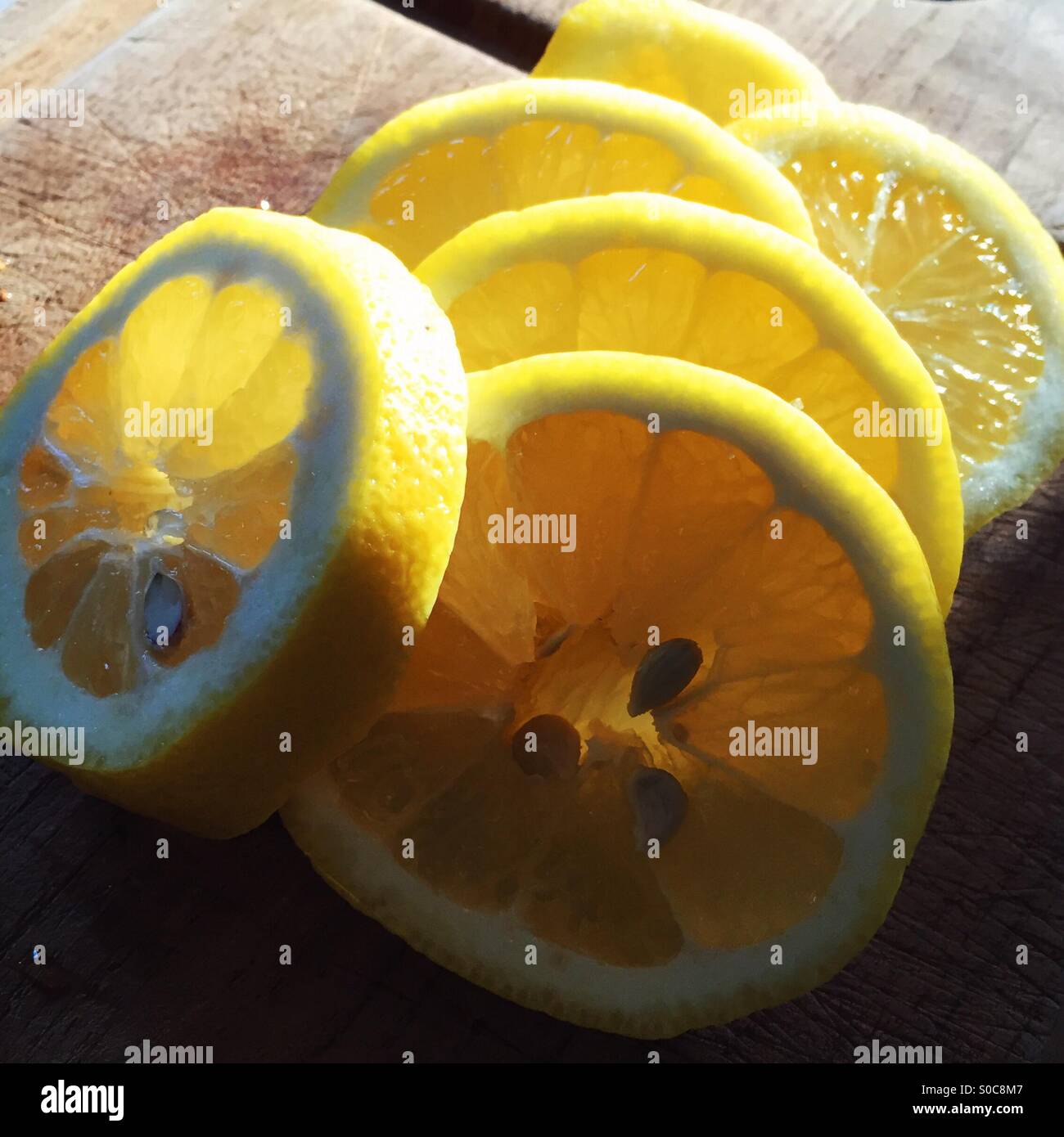 Appena spicchi di limone su un tagliere con la rastrellatura luce illuminando le fette - Immagine stock catturata con smartphone Appena spicchi di limone su un tagliere con la rastrellatura luce illuminando le fette - Immagine stock catturata con smartphone