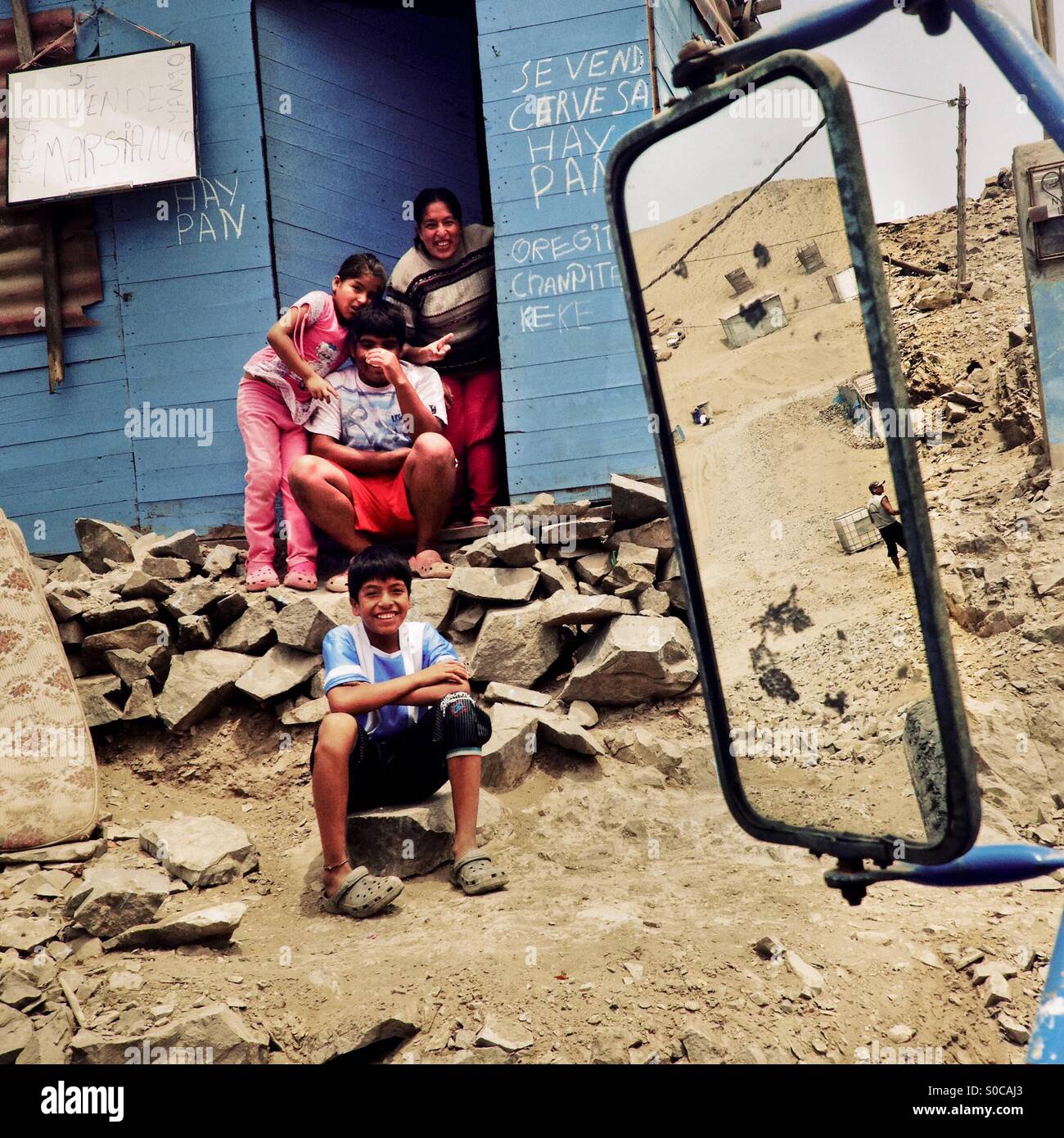 Famiglia Peruviana membri siedono davanti a una casa in legno sulla polvere della collina di Pachacútec, un deserto baraccopoli in Lima, Perù, 20 gennaio 2015. Foto Stock
