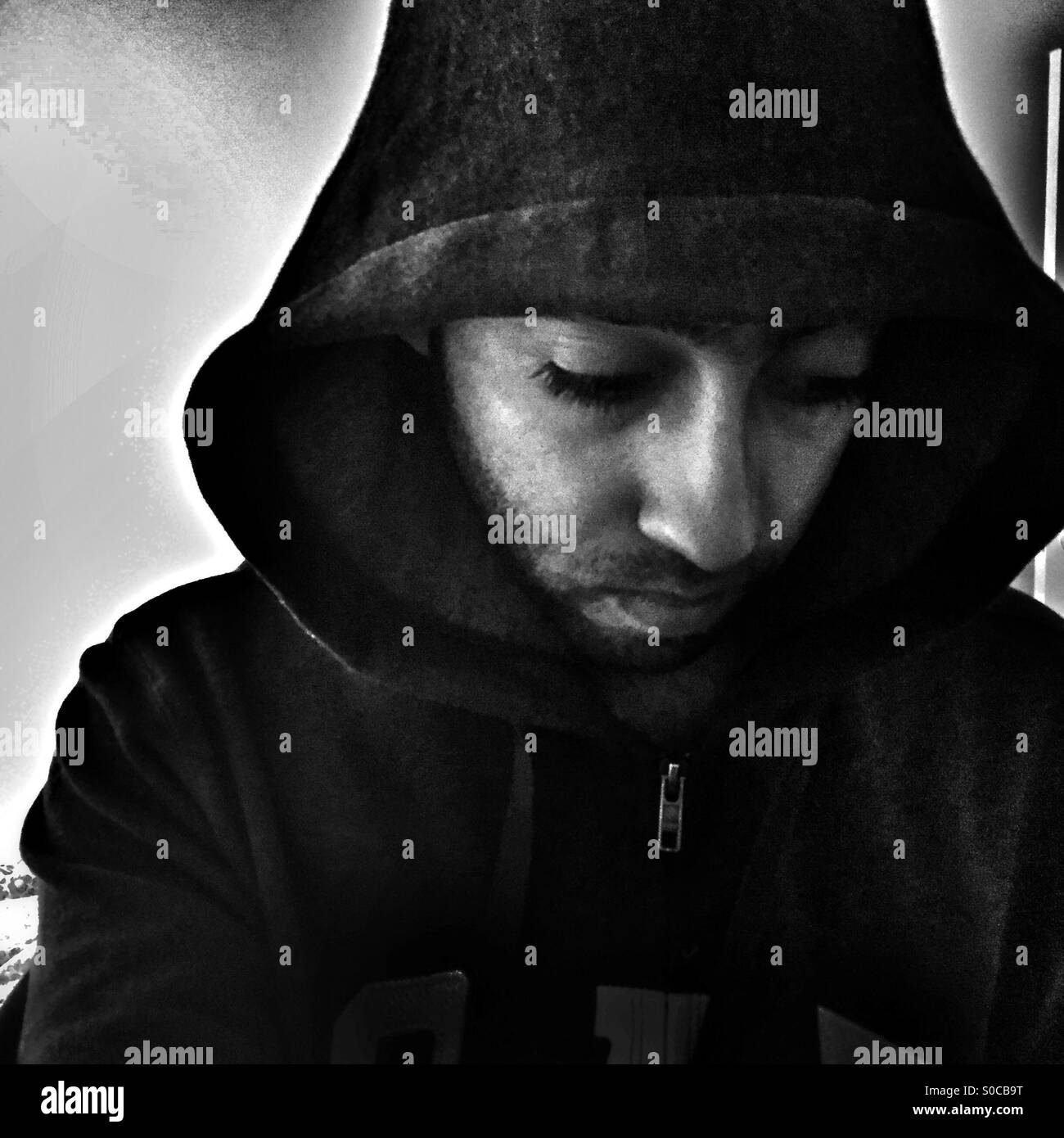 Un ragazzo indossa una felpa con cappuccio guardando verso il basso Foto Stock