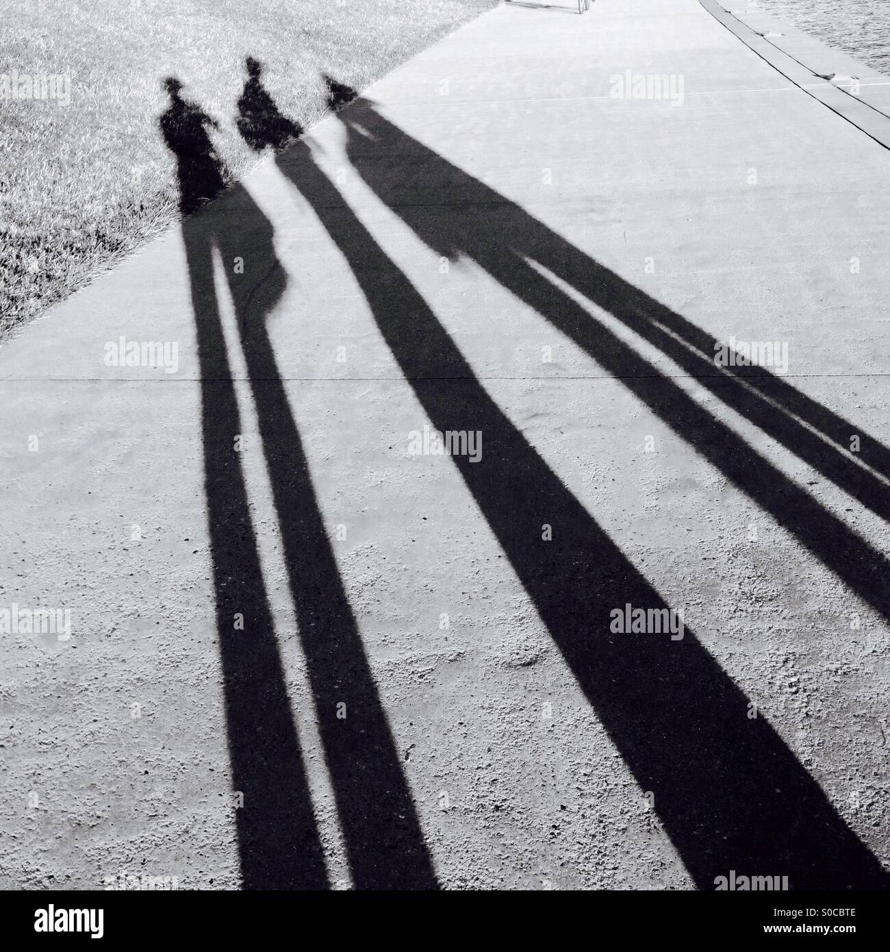A lungo in bianco e nero le ombre di 3 persone Foto Stock