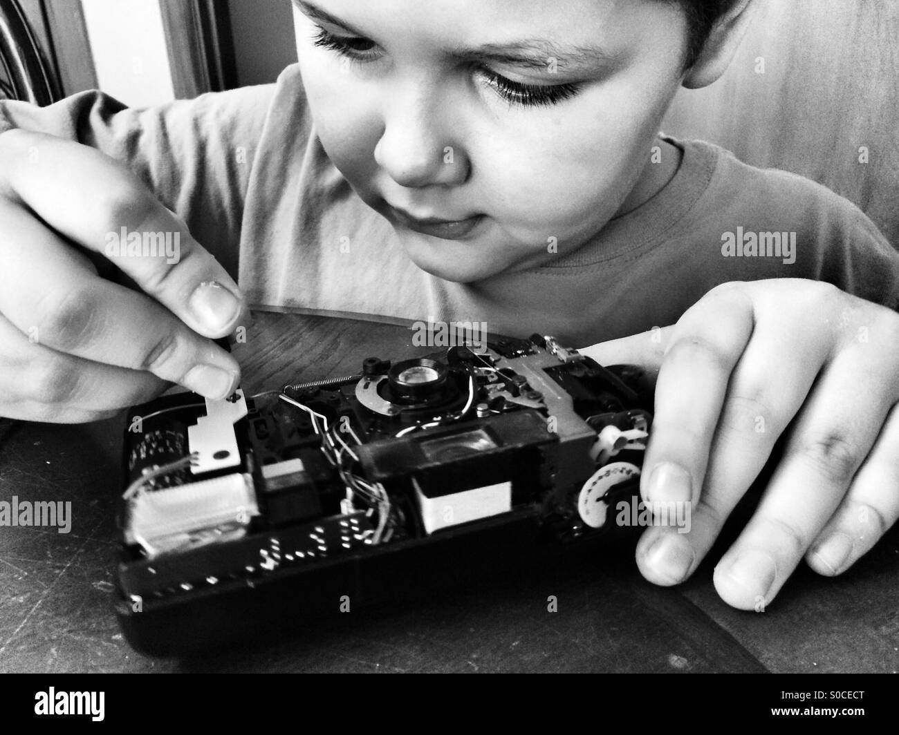 Un ragazzo curioso disassembla una vecchia macchina fotografica Foto Stock