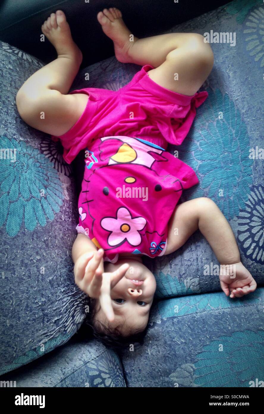 Baby girl sdraiato sul divano e rivolta verso il fotografo Foto Stock