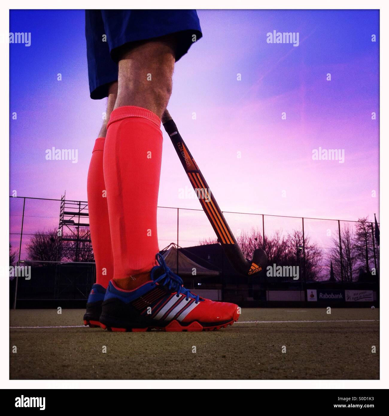 Gambe di hockey con le scarpe e le calze e una mazza da hockey su un campo  di hockey su prato a destra dopo il tramonto Foto stock - Alamy