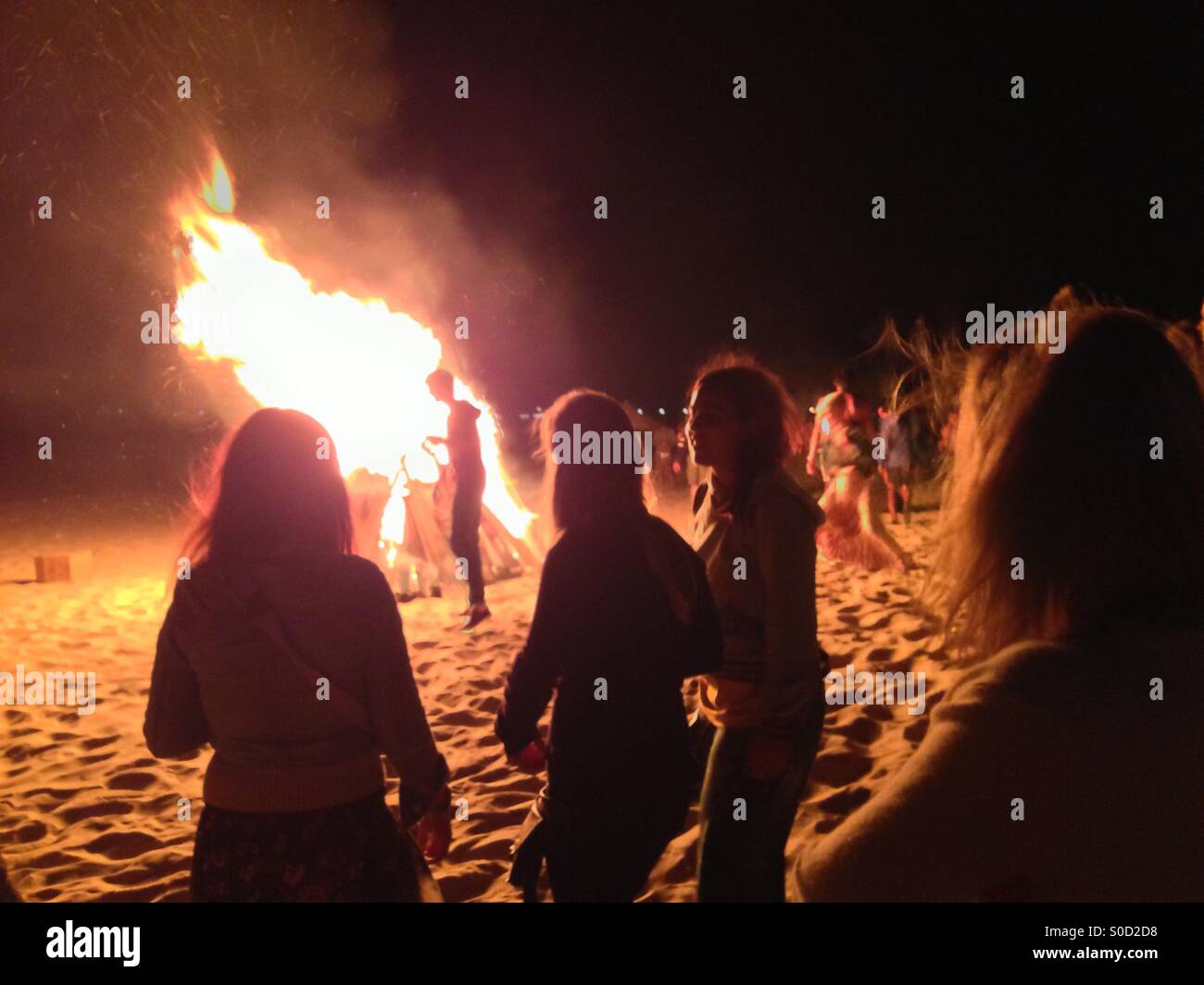 La gente intorno al falò sulla spiaggia party fire sabbia raccogliere raccolte fiamme estate Foto Stock