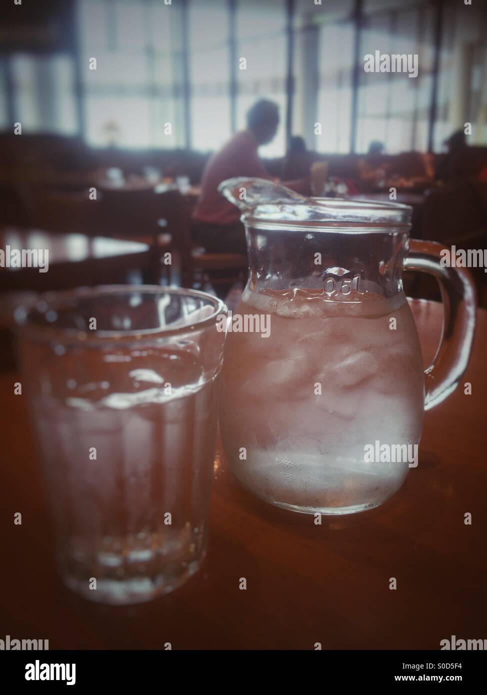 Brocca e bicchiere di acqua ghiacciata in un ristorante. Retrò, aspetto sbiadito. Foto Stock