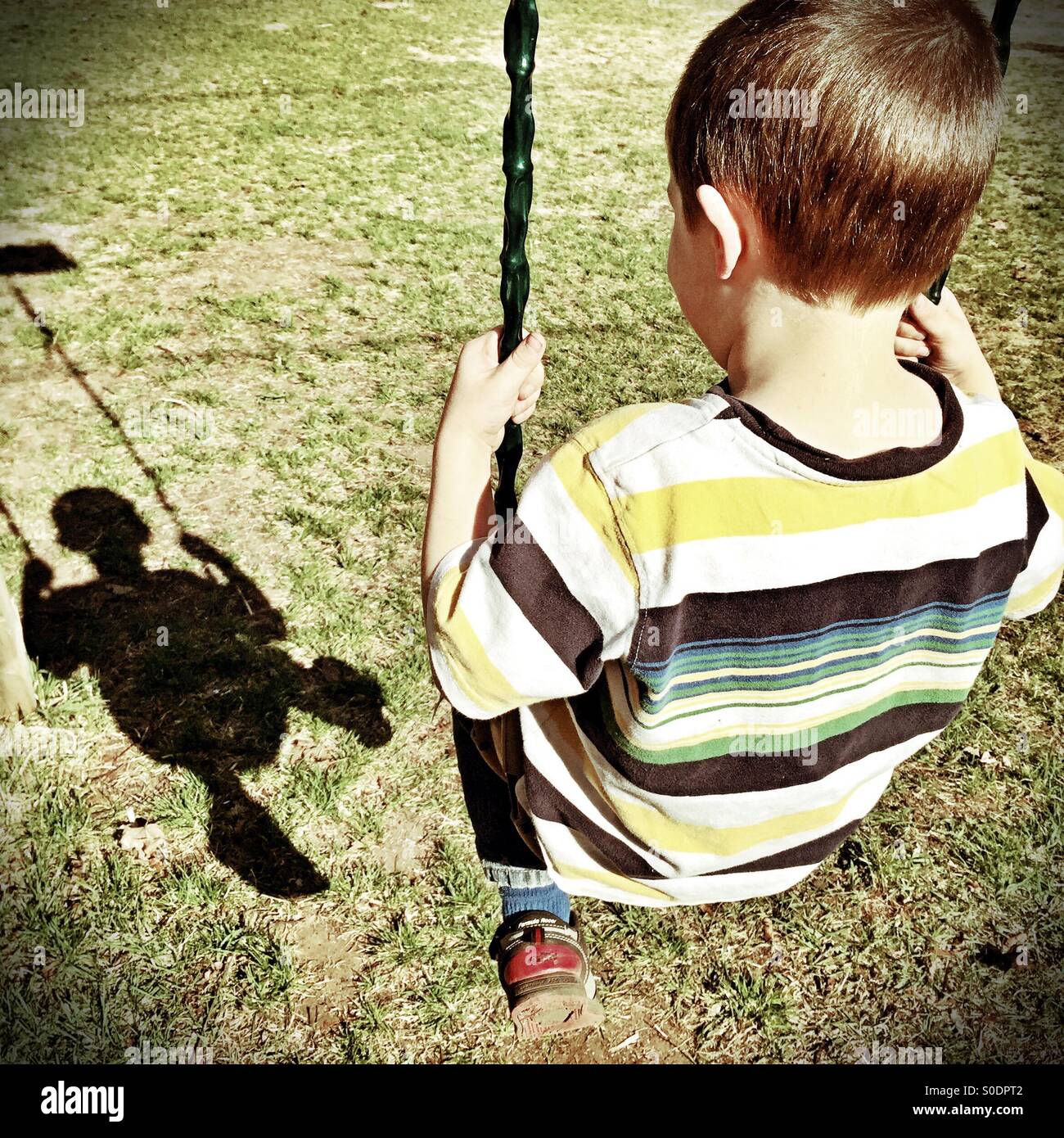 Ragazzo giovane altalene e ammira la shadow image Foto Stock