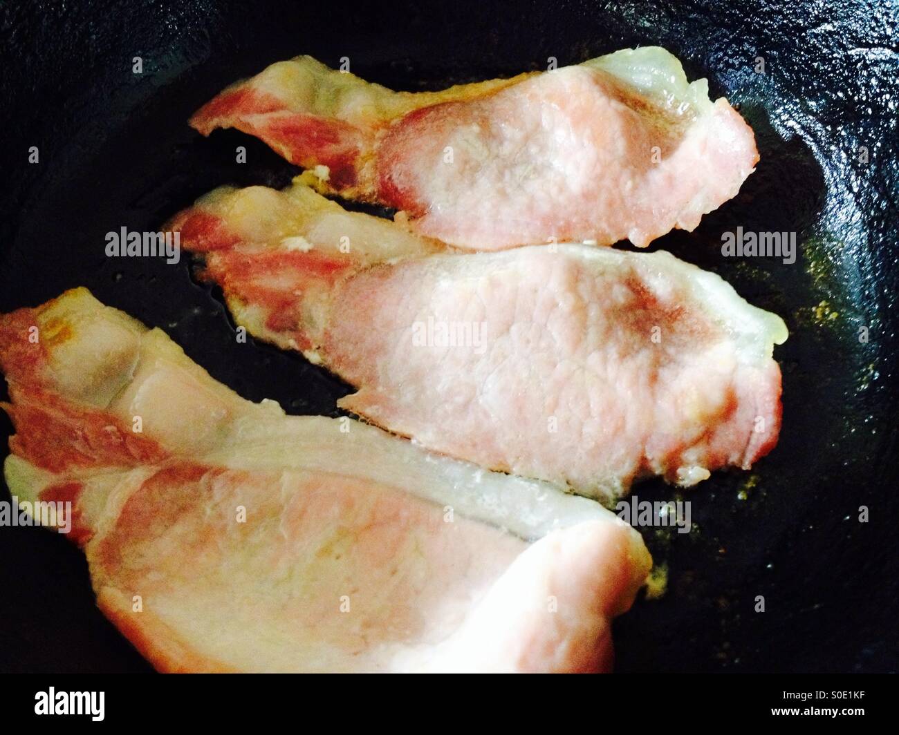 Fattoria di corsia salatura a secco a mano ed essiccato con aria back bacon in padella. - Immagine stock catturata con smartphone