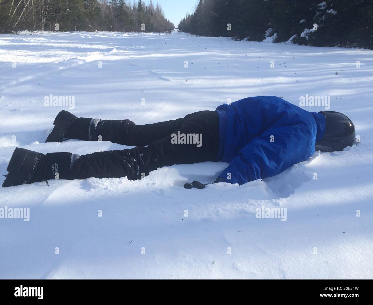 Persona sdraiata a faccia in giù nella neve Foto Stock