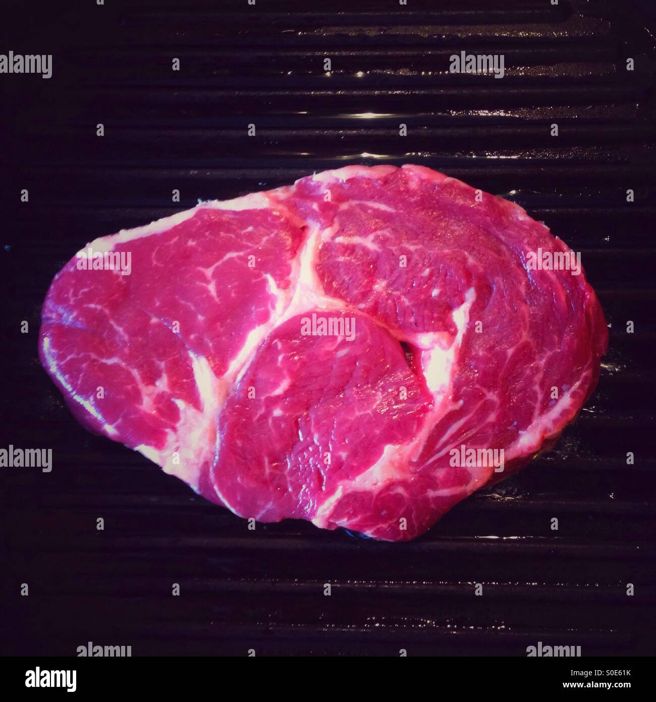 Ribeye sulla piastra pan pronti per essere cucinati - Immagine stock catturata con smartphone