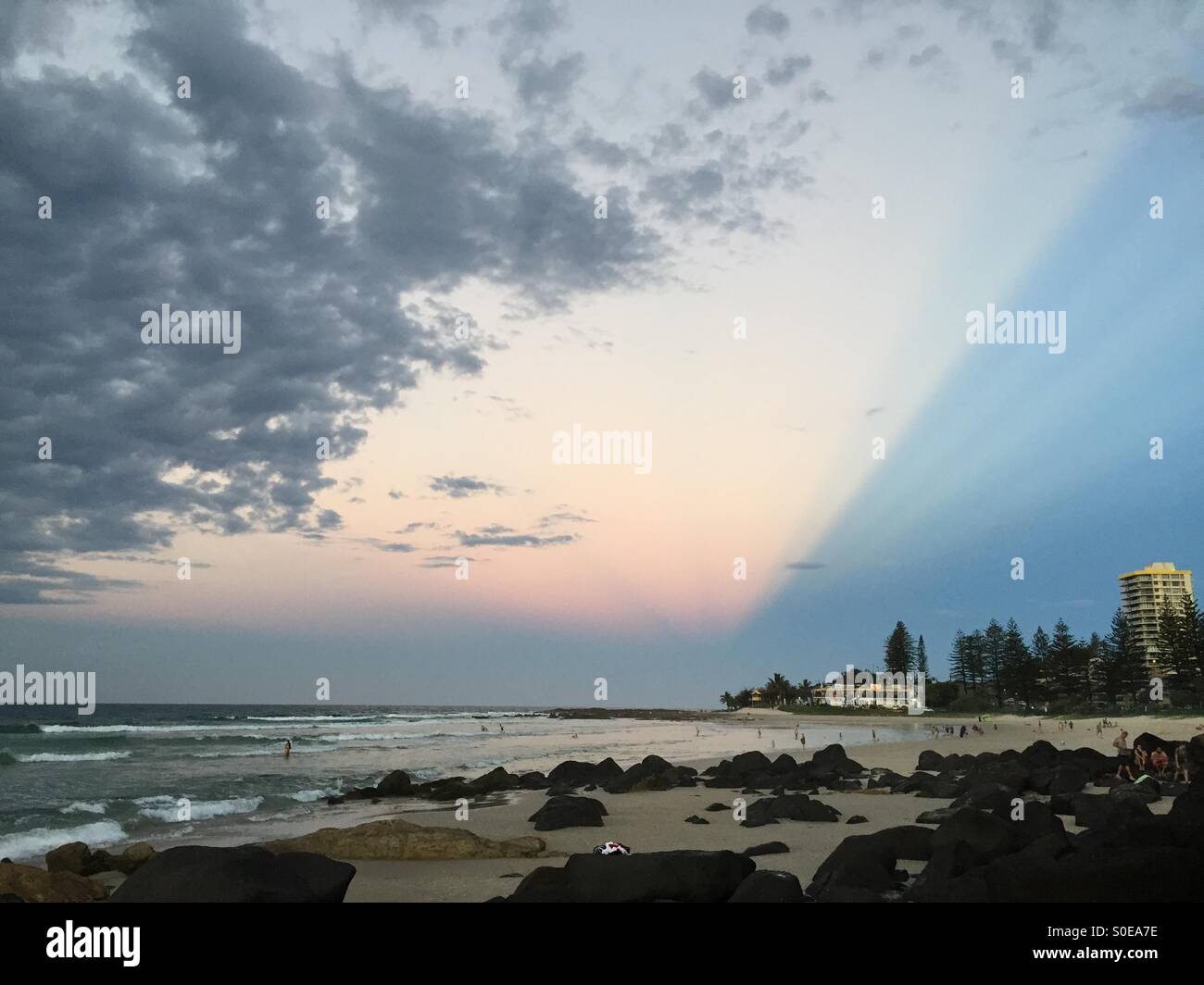 Twilight raggi e cloud al di sopra di Rainbow Bay beach, Coolangatta, Gold Coast Foto Stock