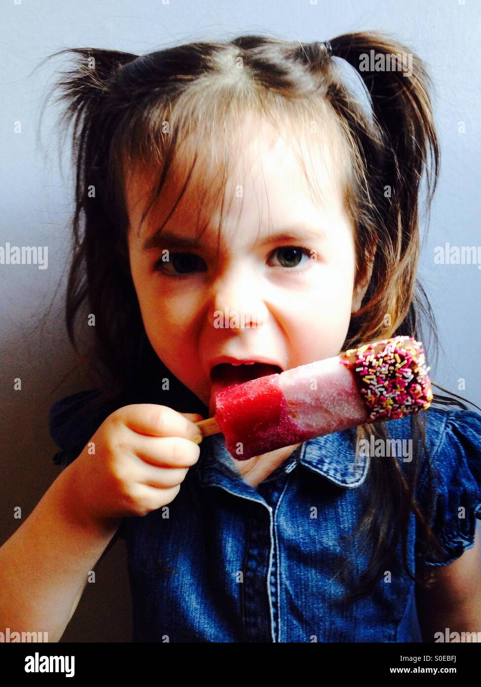 3 anno vecchia ragazza leccare un Fab per lecca-lecca Foto Stock