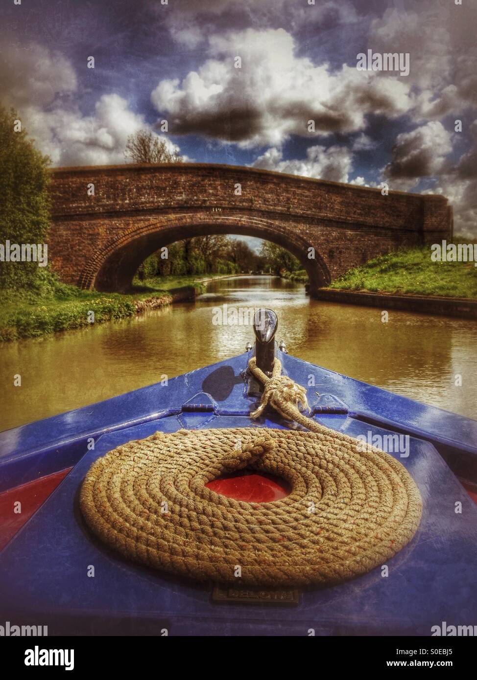Narrowboat avvicinando un ponte al di sopra del Sud Oxford Canal vicino a Cropredy, Oxfordshire, Inghilterra. Foto Stock