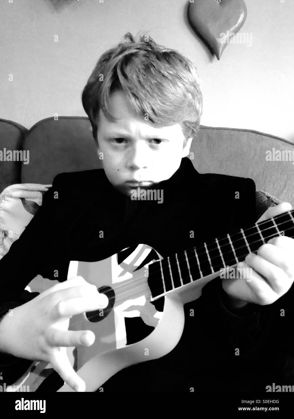 10-anno vecchio ragazzo a suonare la chitarra al suo Suffolk home. Foto Stock