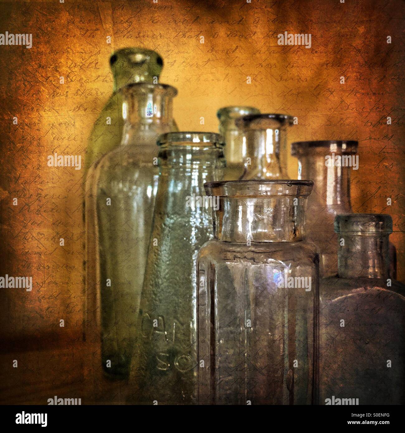 Vecchio, vintage, bottiglie di antiquariato insieme contro un sfondo spiovente con parole scritte visibili. Foto Stock