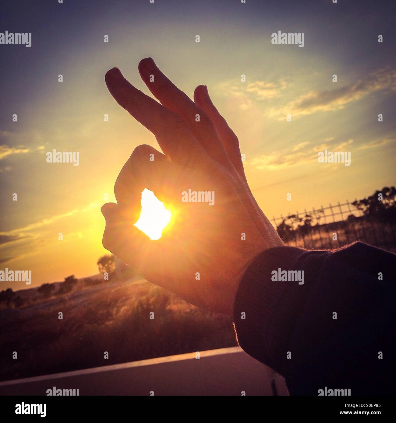 Fine di una giornata perfetta. Mano profilarsi davanti al sole. - Immagine stock catturata con smartphone