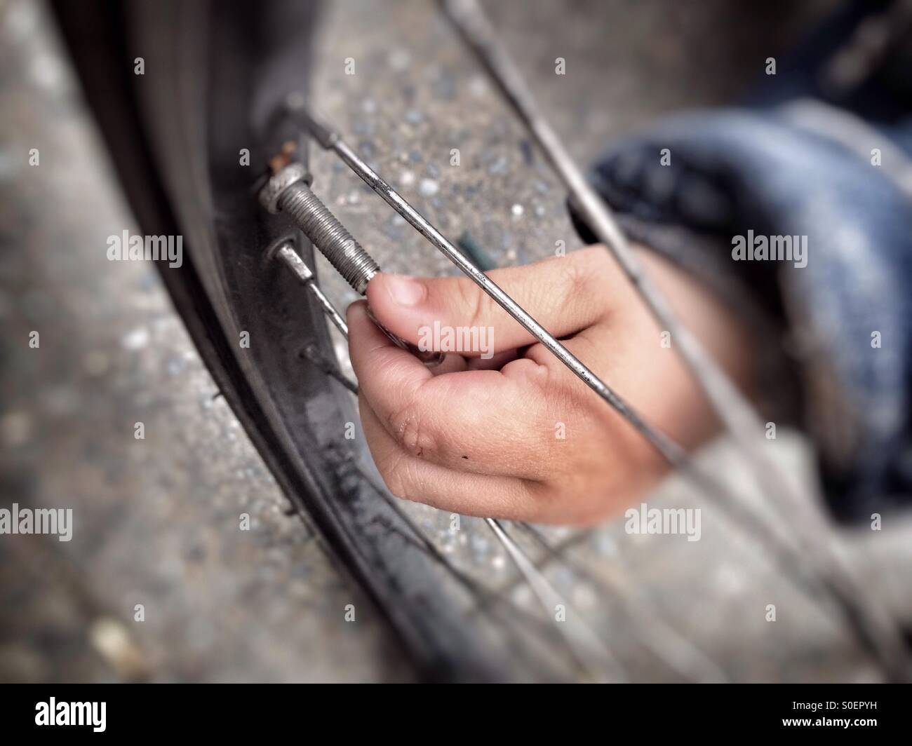 Un bimbo a mano la rimozione del tappo della valvola su di una ruota di bicicletta Foto Stock