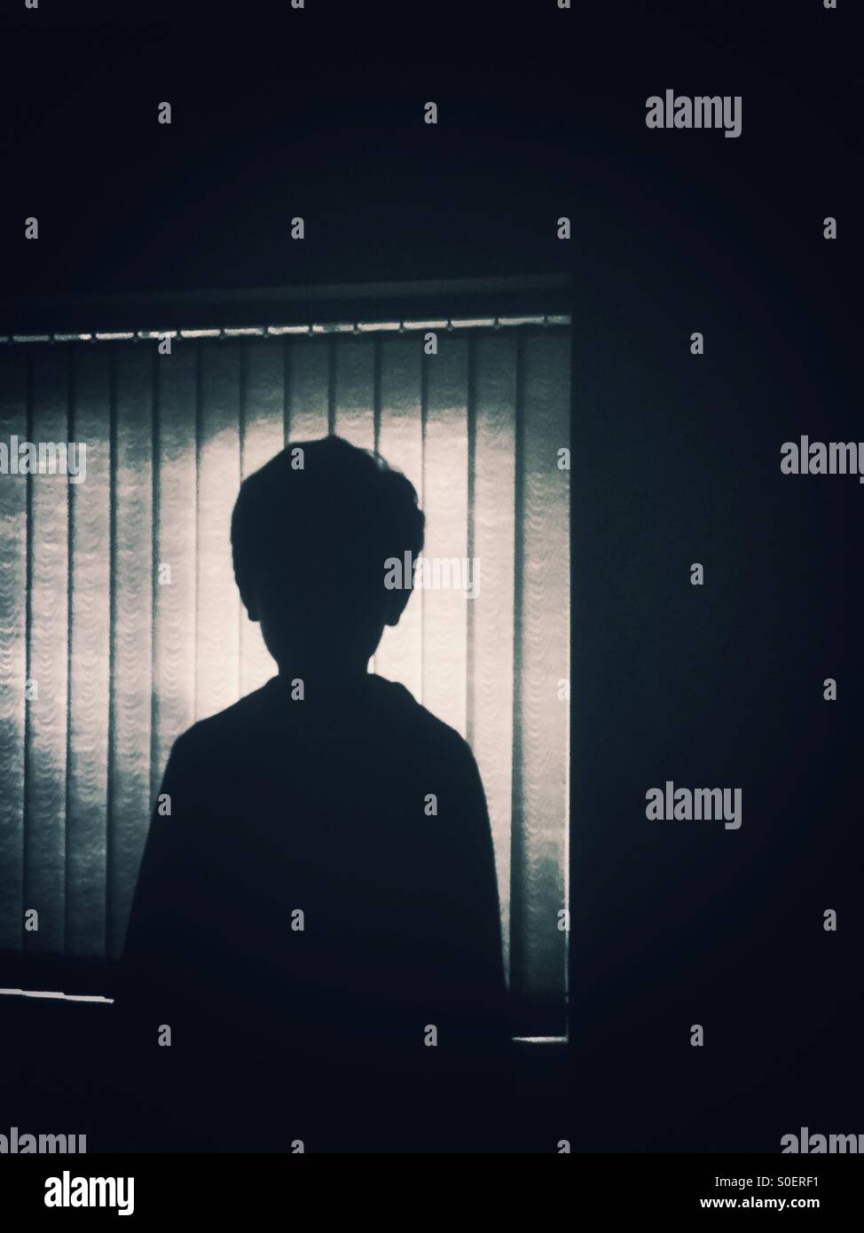 Silhouette di un ragazzino dalla finestra Foto Stock