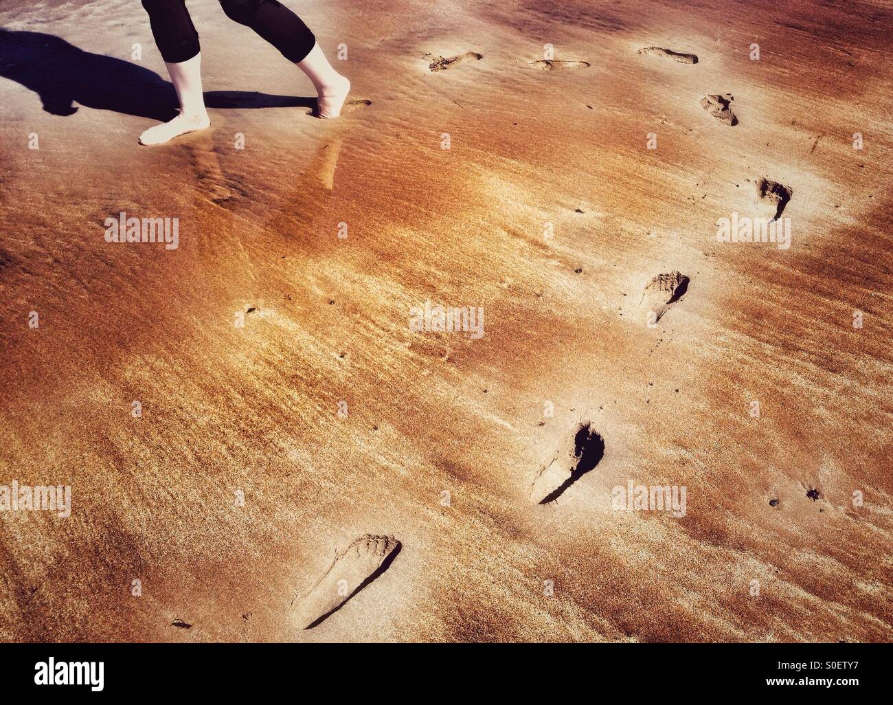 Footprints curvando round di sabbia in spiaggia Foto Stock