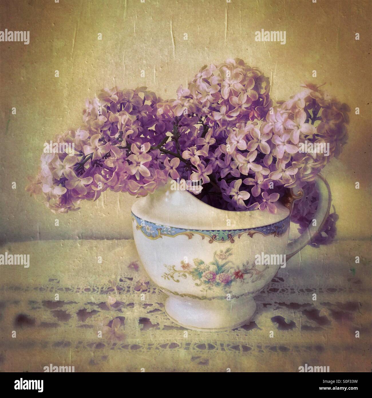 Bouquet di viola lillà in crema di antiquariato brocca su un pezzo di merletto antico - Immagine stock catturata con smartphone