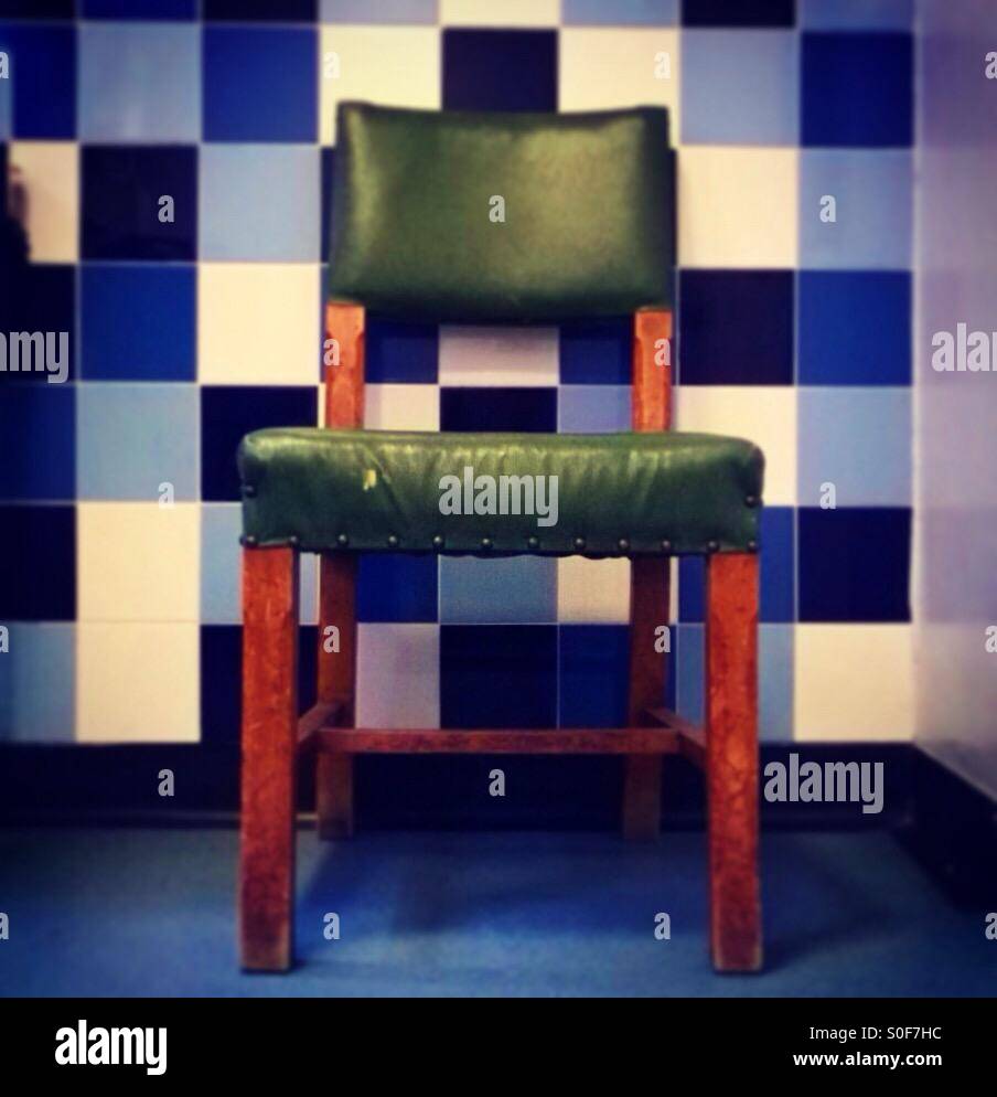 Sedia verde blu contro la parete a scacchi Foto Stock