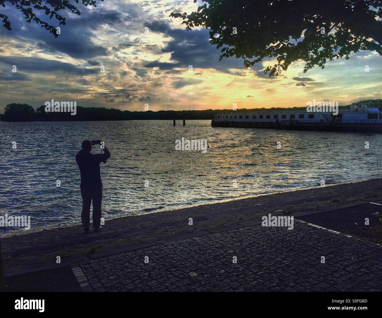 Uomo di far scattare il tramonto sul lago Foto Stock